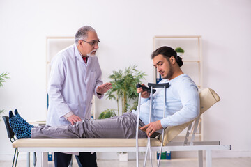 Young leg injured man visiting old doctor osteopath