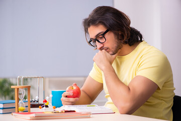 Young male student physicist preparing for exams in the classroo