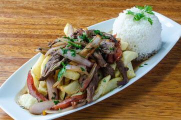 Peruvian dish called Lomo Saltado made of tomato, beef meat and onions mixed with French fries and served with rice.