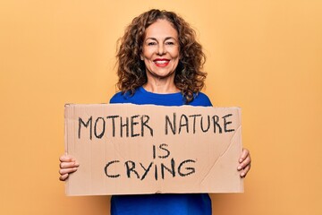 Fototapeta na wymiar Middle age woman asking for environment holding banner with mother nature is crying message looking positive and happy standing and smiling with a confident smile showing teeth