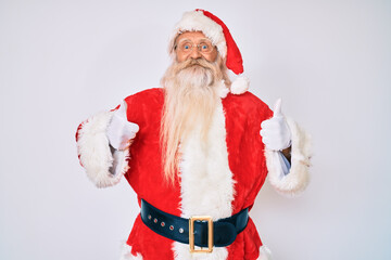 Old senior man with grey hair and long beard wearing santa claus costume with suspenders success sign doing positive gesture with hand, thumbs up smiling and happy. cheerful expression and winner