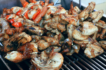 chicken skewers, chicken wings and roasted pork cooking on a street BBQ