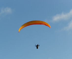 A beautiful view of a paraglide flying gliding on a clear blue sky at the golden hour with a nice wind windy breeze on a sunny day 