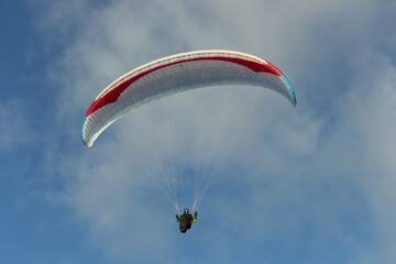 A beautiful view of a paraglide flying gliding on a clear blue sky at the golden hour with a nice wind windy breeze on a sunny day 