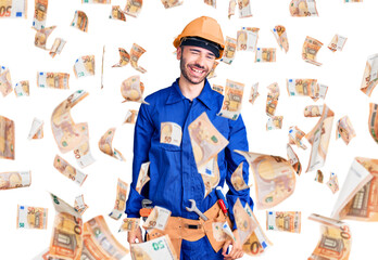 Young hispanic man wearing worker uniform winking looking at the camera with sexy expression,...