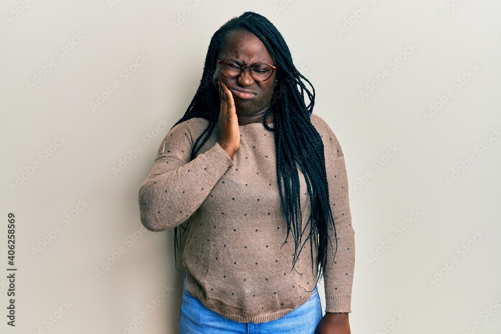 Poster young black woman with braids wearing casual clothes and glasses touching mouth with hand with painf