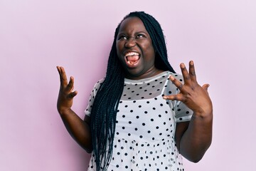 Young black woman with braids wearing casual clothes crazy and mad shouting and yelling with aggressive expression and arms raised. frustration concept.