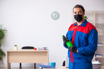 Young male contractor disinfecting office