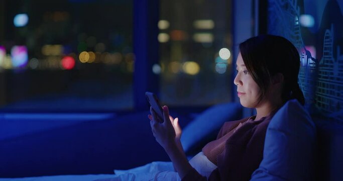 Woman check on smart phone and sit on bed in the evening