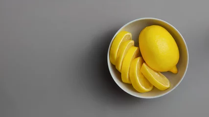 Gelbe Zitronen in grauer Platte auf grauem Hintergrund. Farben des Jahres 2021 Pantone Illuminating und Ultimate Grey © Евгения Рубцова