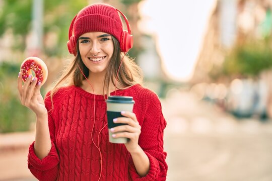 Young hispanic woman having breakfast using headphones at the city.