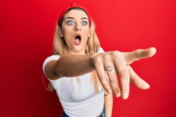 Young caucasian woman wearing casual white t shirt pointing with finger surprised ahead, open mouth...