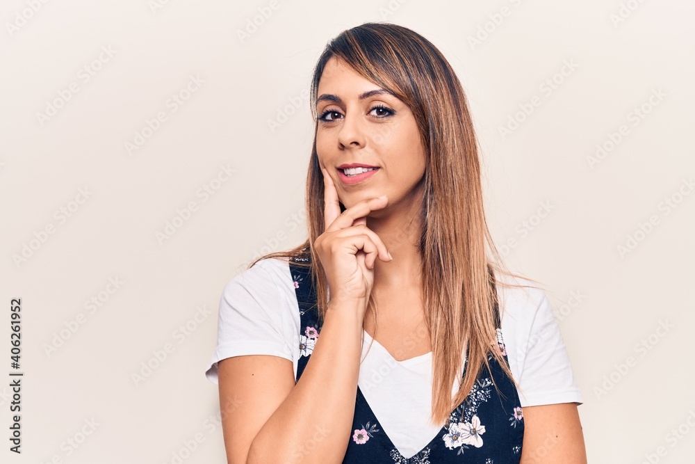 Wall mural young beautiful woman wearing casual floral dress smiling looking confident at the camera with cross