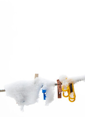 winter background: clothesline covered with snow, several colored clothespins, selective focus