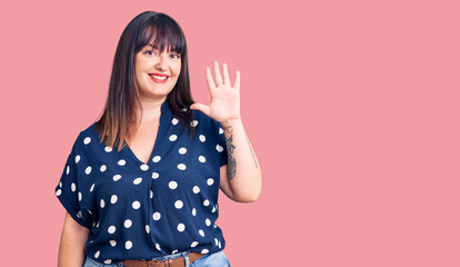 Young plus size woman wearing casual clothes showing and pointing up with fingers number five while smiling confident and happy.