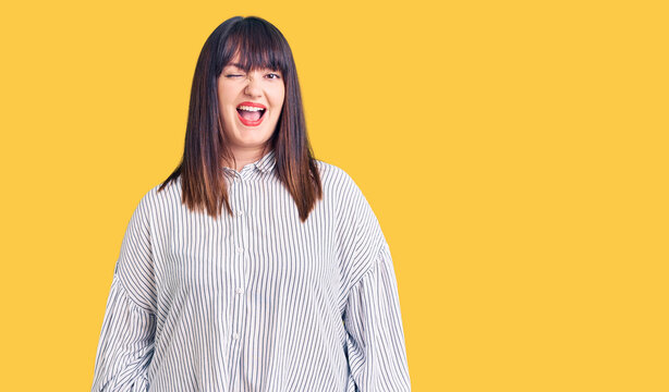 Young plus size woman wearing casual clothes winking looking at the camera with sexy expression, cheerful and happy face.