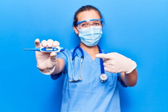 Young blonde woman wearing doctor uniform and coronavirus protection holding help reminder smiling happy pointing with hand and finger