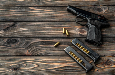 Pistol and cartridges for it on a wooden background. A short-barreled weapon for self-defense