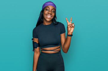Young african american woman wearing sportswear smiling with happy face winking at the camera doing...