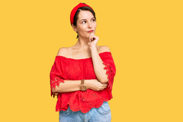 Young brunette woman with short hair wearing casual summer clothes and diadem with hand on chin thinking about question, pensive expression. smiling and thoughtful face. doubt concept.