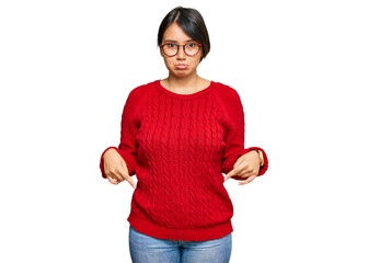 Young beautiful hispanic woman with short hair wearing casual sweater and glasses pointing down...