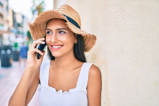 Young latin girl wearing summer style talking on the smartphone leaning on the wall.