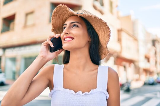 Young latin girl wearing summer style talking on the smartphone at street of city.