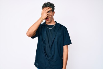 Young handsome man wearing casual clothes peeking in shock covering face and eyes with hand,...