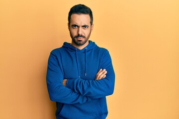 Young hispanic man wearing casual clothes skeptic and nervous, disapproving expression on face with crossed arms. negative person.