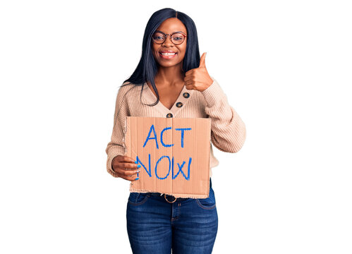 Young african american woman holding act now banner smiling happy and positive, thumb up doing excellent and approval sign
