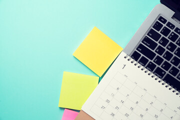 close up of calendar and computer laptop on the green table background, planning for business meeting or travel planning concept