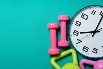 Time for exercising clock and dumbbell with green table background