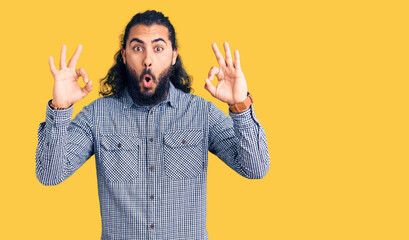 Young arab man wearing casual clothes looking surprised and shocked doing ok approval symbol with fingers. crazy expression