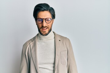 Young hispanic man wearing business jacket and glasses winking looking at the camera with sexy...