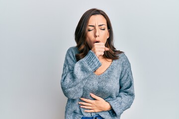 Young brunette woman wearing casual winter sweater feeling unwell and coughing as symptom for cold...