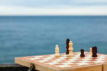 Playing chess on a Board on the beach. Chessboard on the background of the sea on a Sunny day. Vacation on the coast.