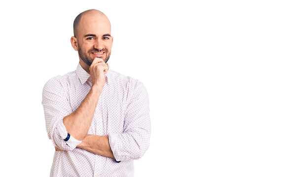 Young handsome man wearing elegant shirt looking confident at the camera with smile with crossed arms and hand raised on chin. thinking positive.