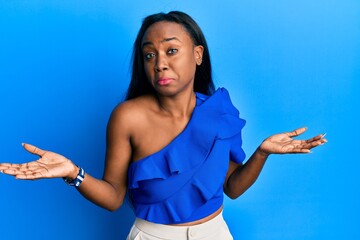 Young african woman wearing casual clothes over blue background clueless and confused expression...