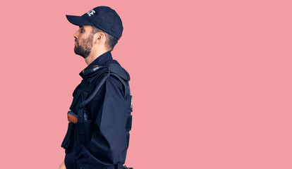 Young handsome man with beard wearing police uniform looking to side, relax profile pose with...
