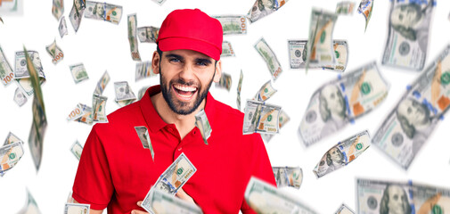 Young handsome man with beard wearing delivery uniform smiling and laughing hard out loud because...