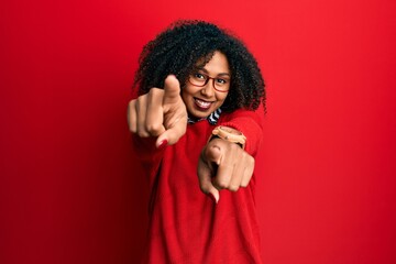 Beautiful african american woman with afro hair wearing sweater and glasses pointing to you and the...