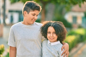 Adorable latin brother and sister hugging at the park.