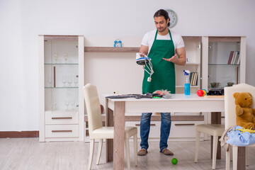 Young male contractor cleaning the flat after kids' party