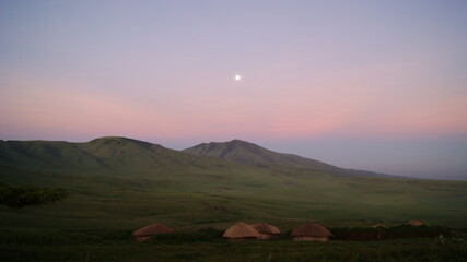 Early morning moon over a Maasai village.  East Africa.