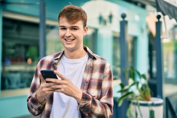 Young caucasian man smiling happy using smartphone at the city.