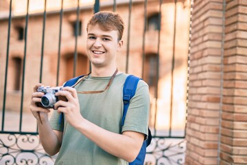 Young caucasian tourist man smiling happy using vintage camera at the city.