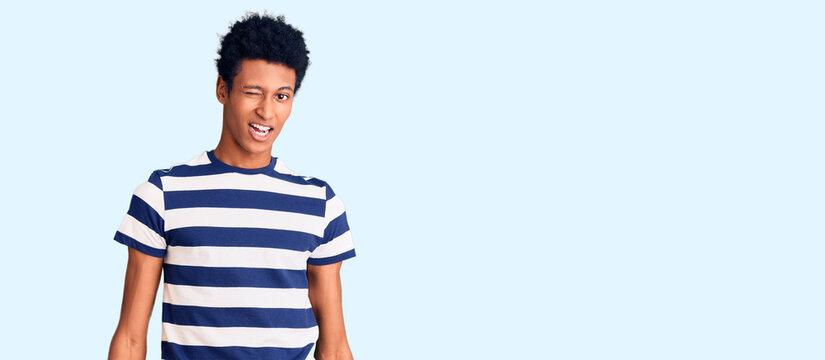 Young african american man wearing casual clothes winking looking at the camera with sexy expression, cheerful and happy face.