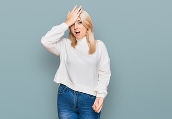 Young caucasian woman wearing casual winter sweater surprised with hand on head for mistake,...