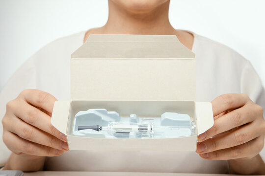 female hands holding package box with syringe of healing medicine ready to inject
