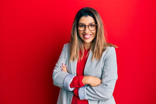 Beautiful brunette woman wearing business shirt and glasses happy face smiling with crossed arms looking at the camera. positive person.